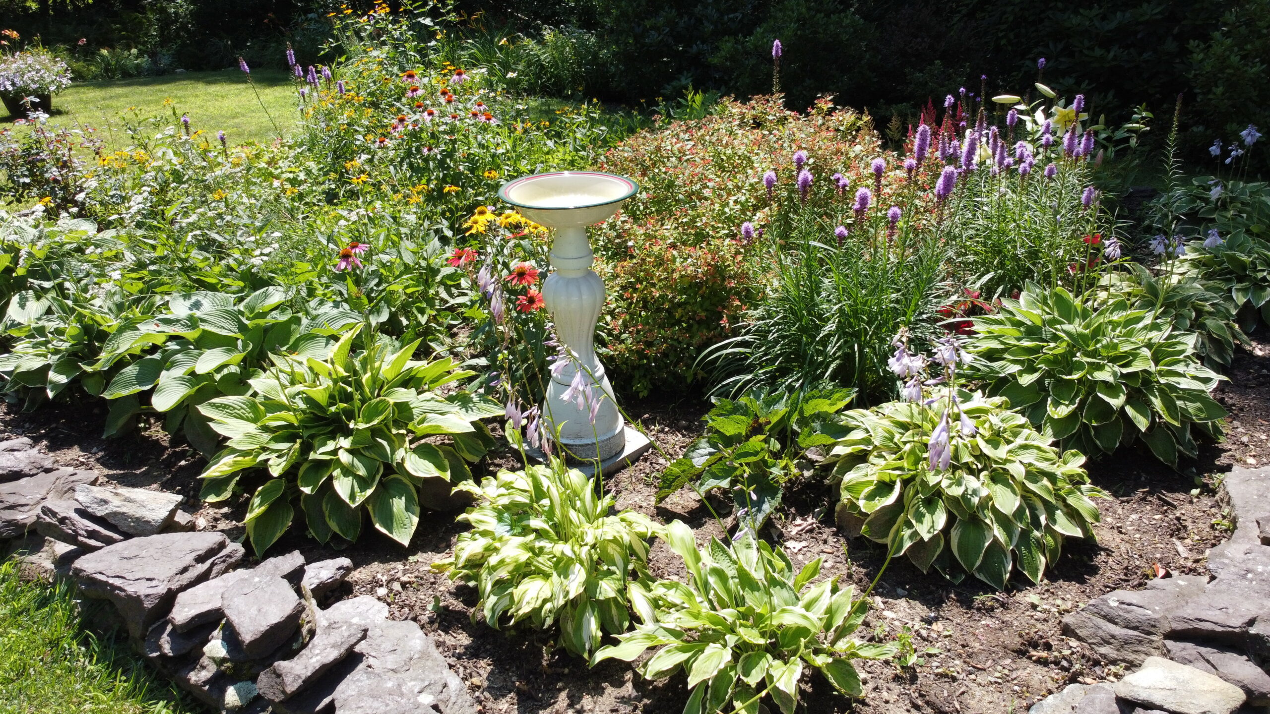 handmade birdbath in the middle of a garden bed