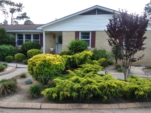 front of house with lots of evergreen shrubs