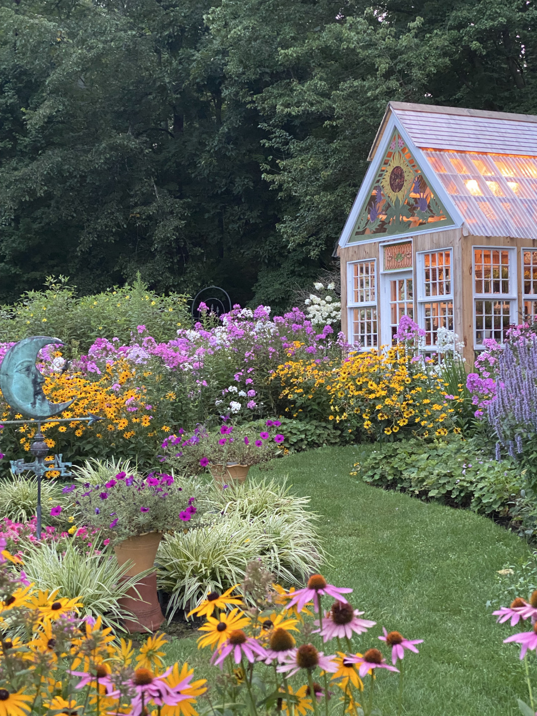 big summer plants in bloom leading to greenhouse