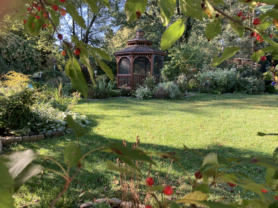 A gazebo invites you to walk across the grass and sit to enjoy the garden.