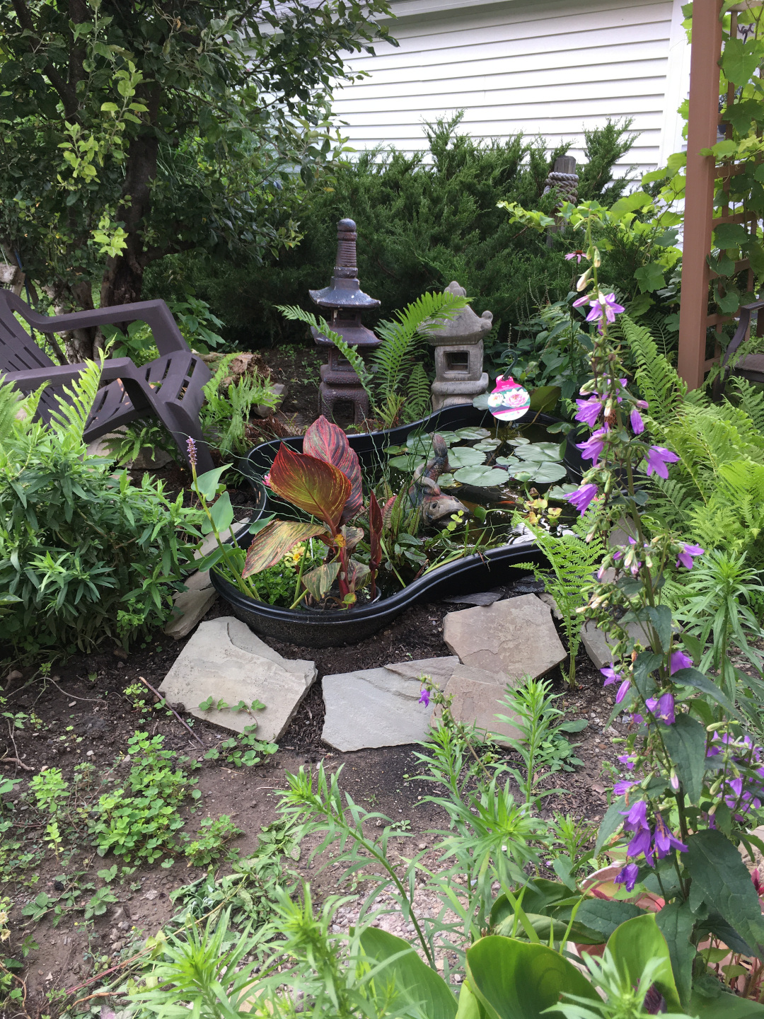 The new pod sitting in the garden, full of life, and with a chair positioned where the gardener can sit and enjoy watching their fish.