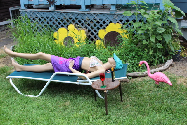 mannequin laying on a lounge chair in a garden