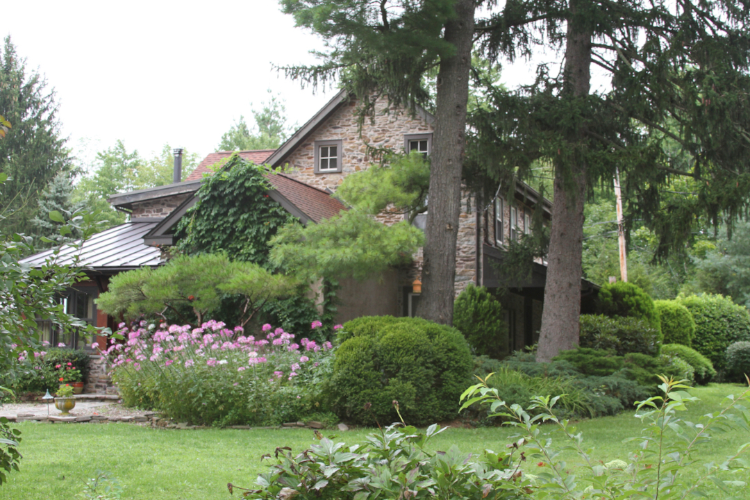 historic home surrounded by evergreen shrubs and pink flowers