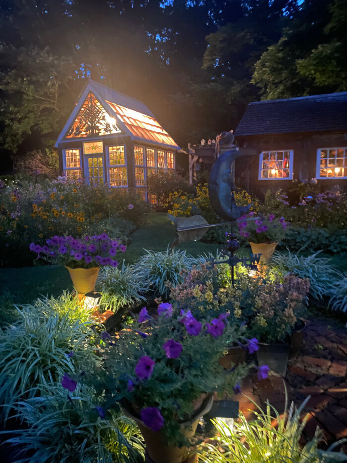 greenhouse at night surrounded by flowers of different colors