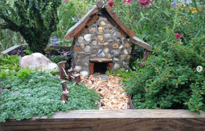 mini garden that has a mini stone house as a focal point