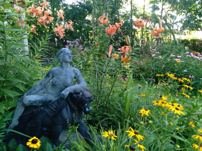 stone statue of woman surrounded by yellow and orange flowers