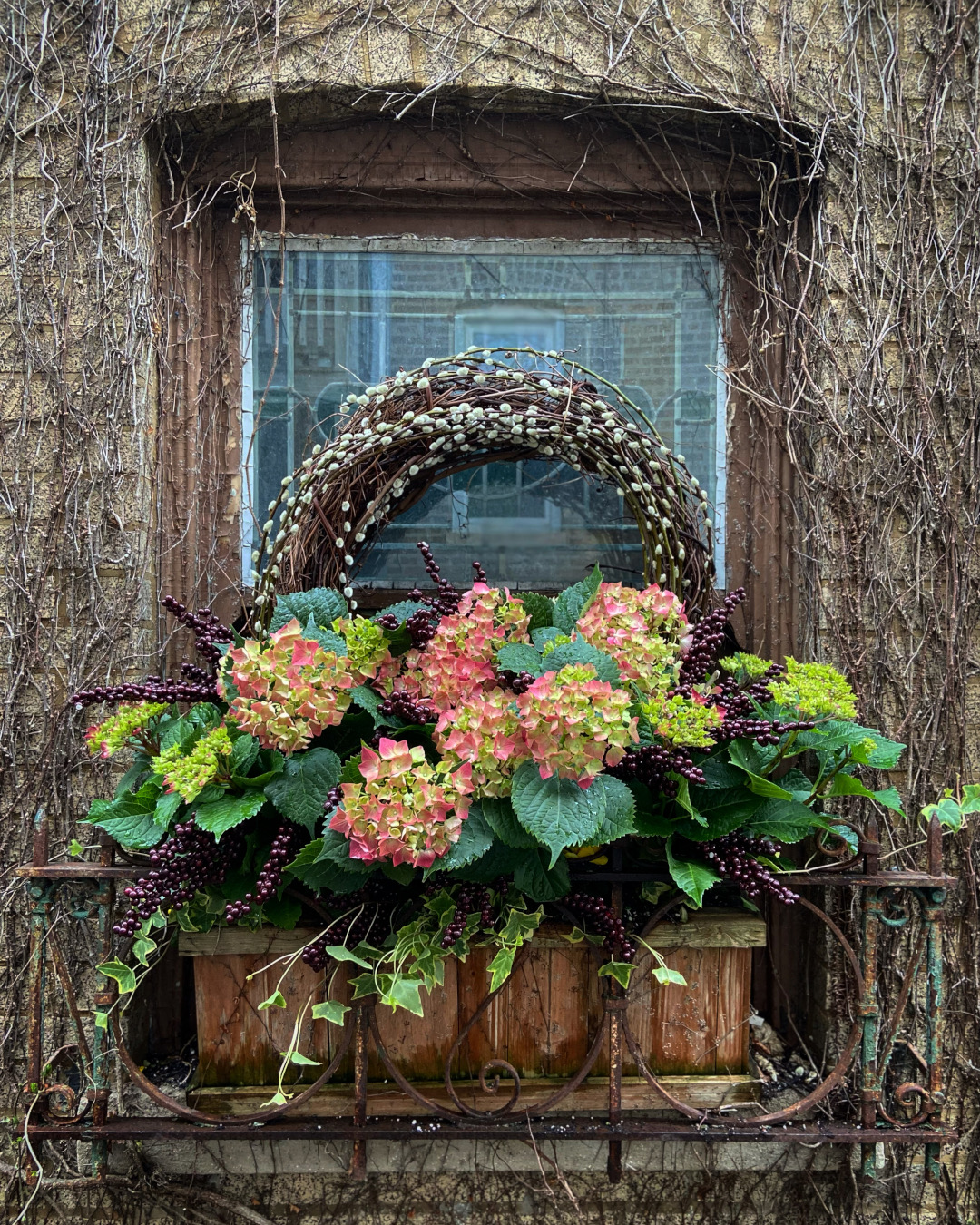 Caja de ventana con hortensias rosas y ramas y bayas.