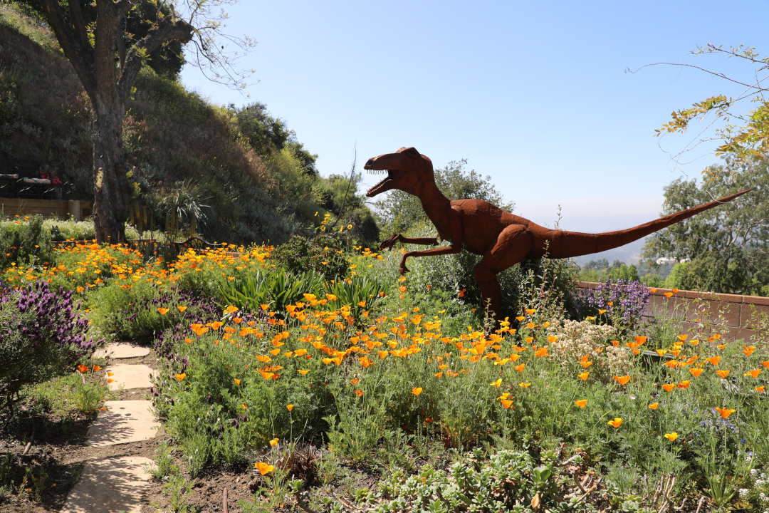 large dinosaur statue in a meadow garden