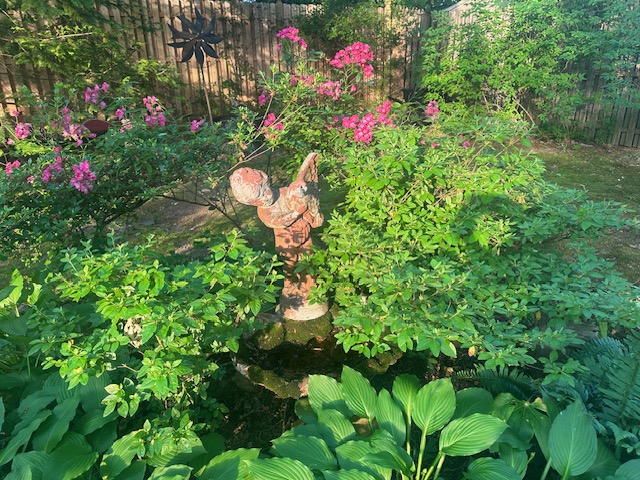 Estatua de jardín rodeada de plantas exuberantes