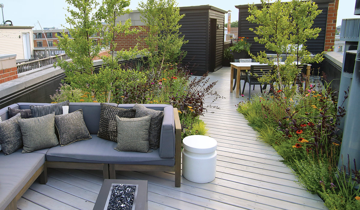 Sala de estar al aire libre en el techo con pequeñas camas de jardín alrededor