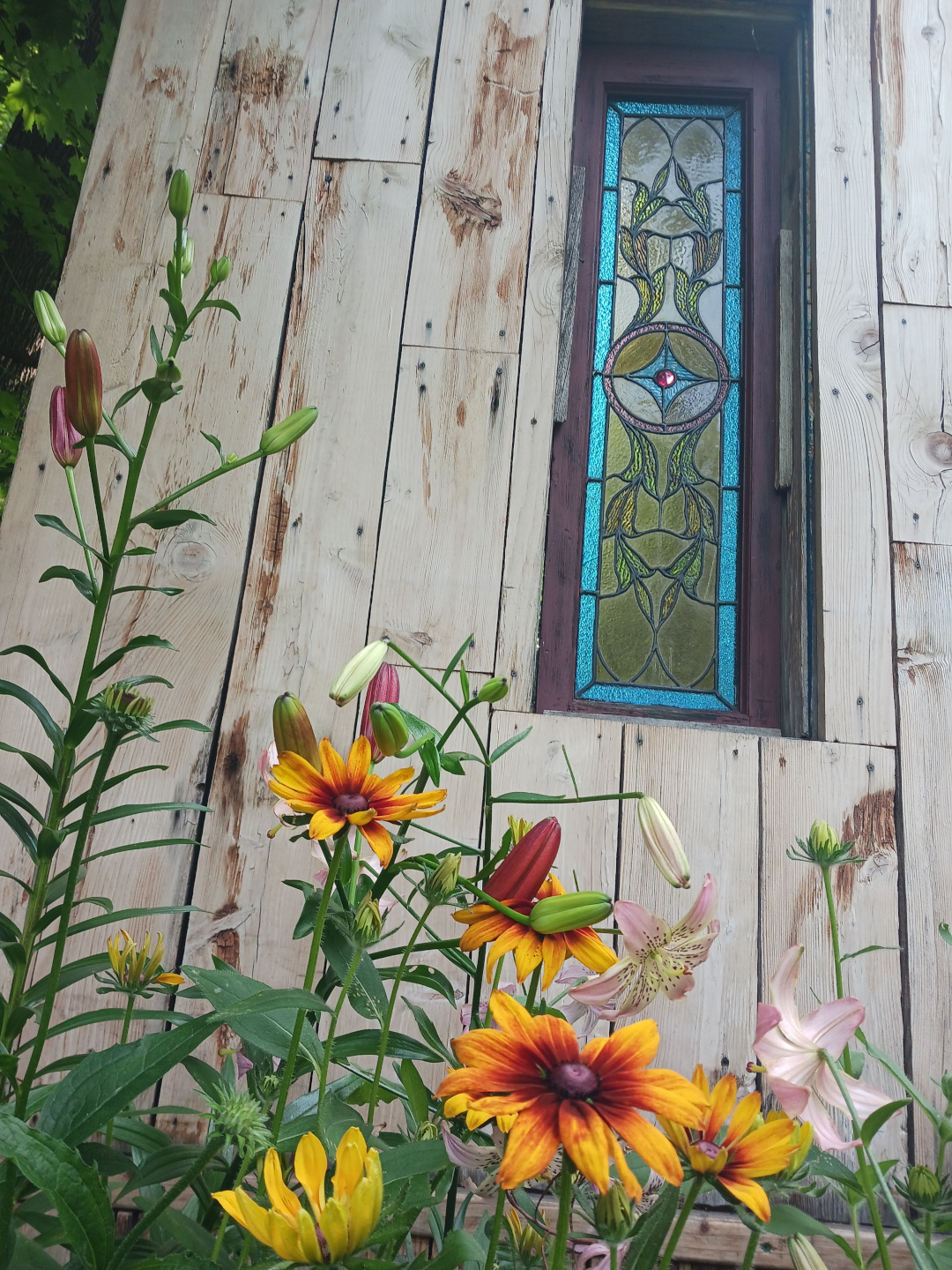 various summer flowers next to a stained glass window