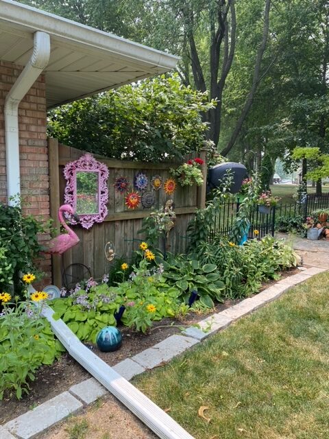 various colorful garden art along a small fence