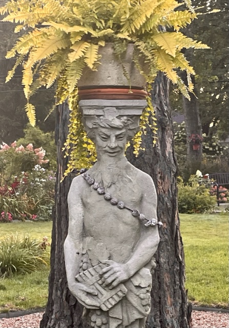 potted variegated fern on top of stone statue