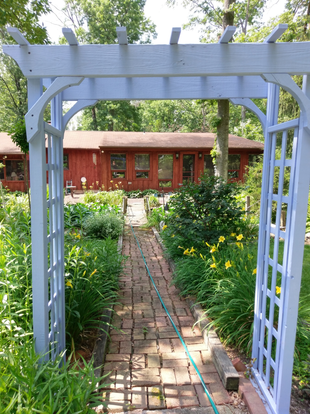 white arbor over a brick path leading to house