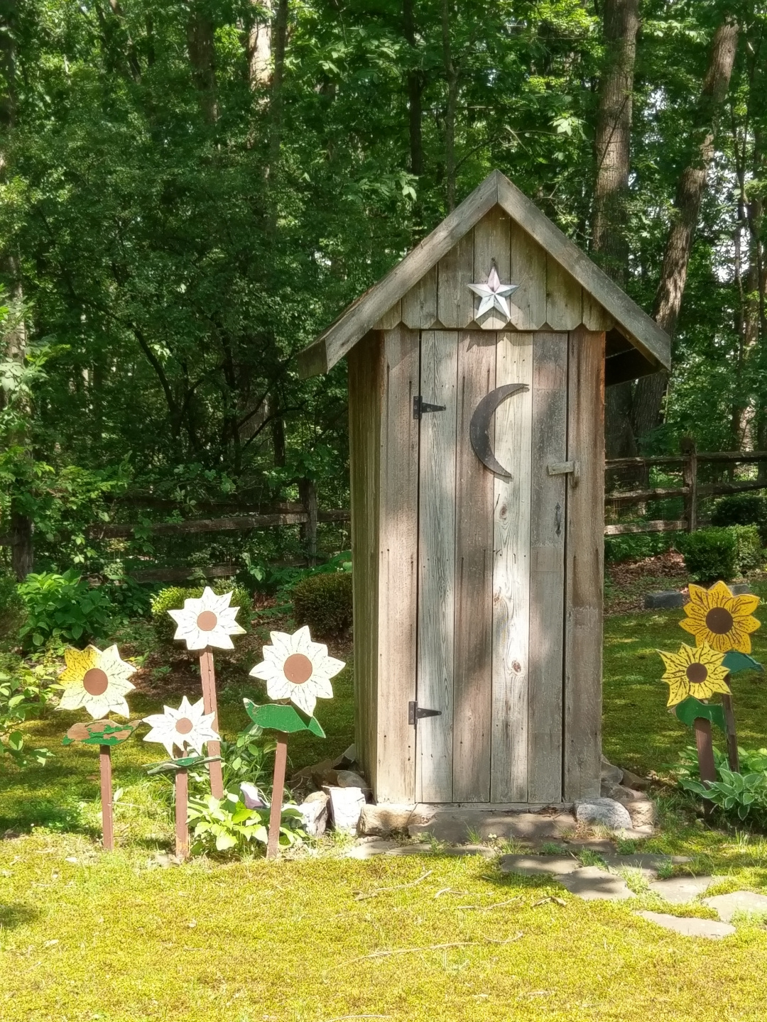 small outhouse with wooden flowers around