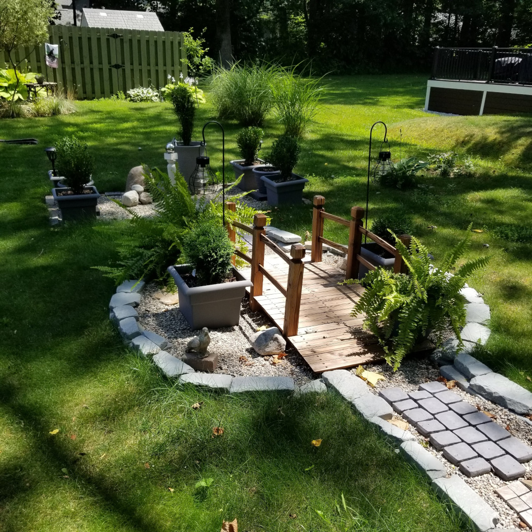 garden path with small bridge with potted ferns around