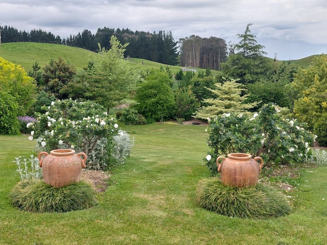 large terracotta pots in front of garden beds