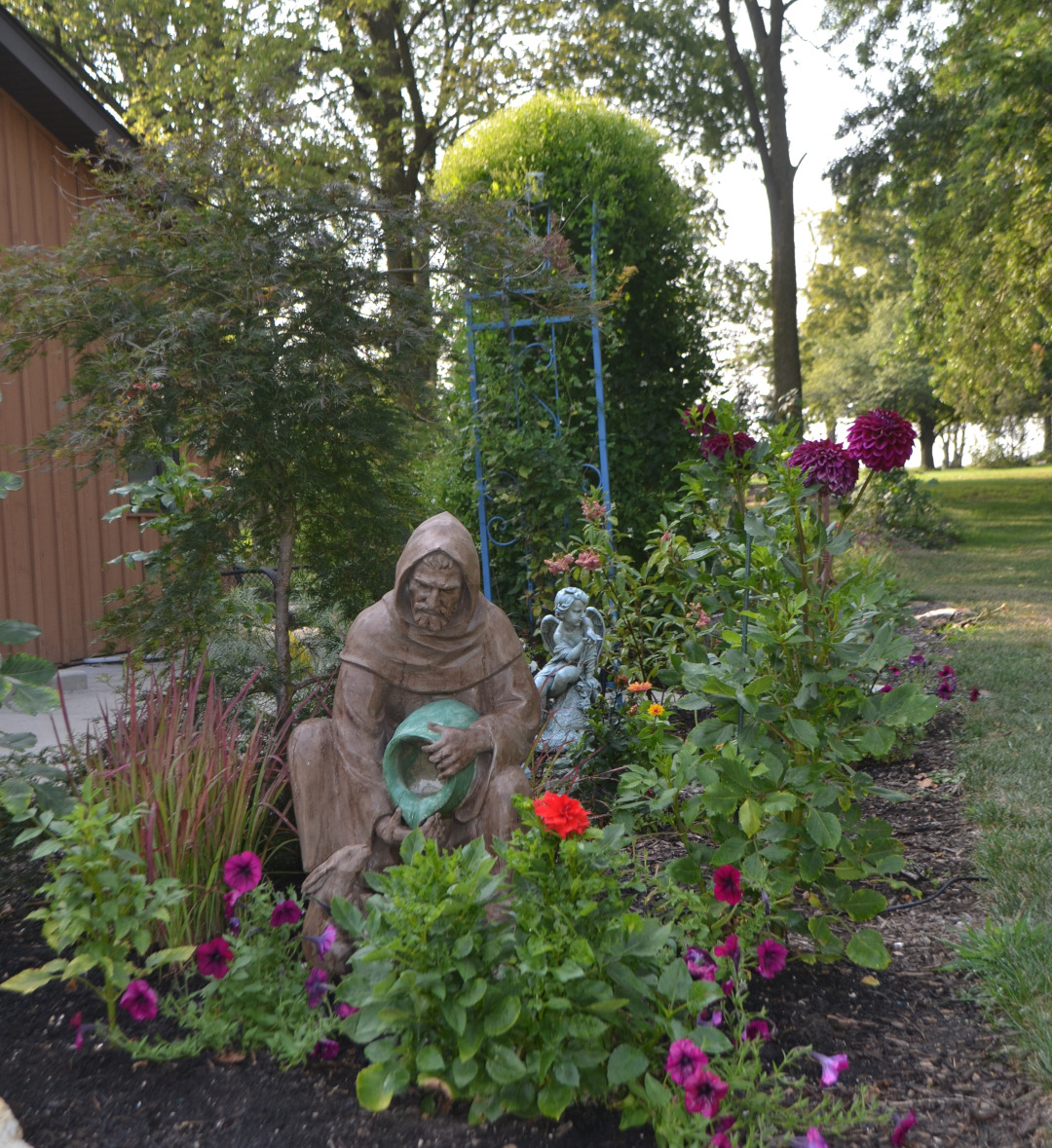 statue in middle of flower garden bed