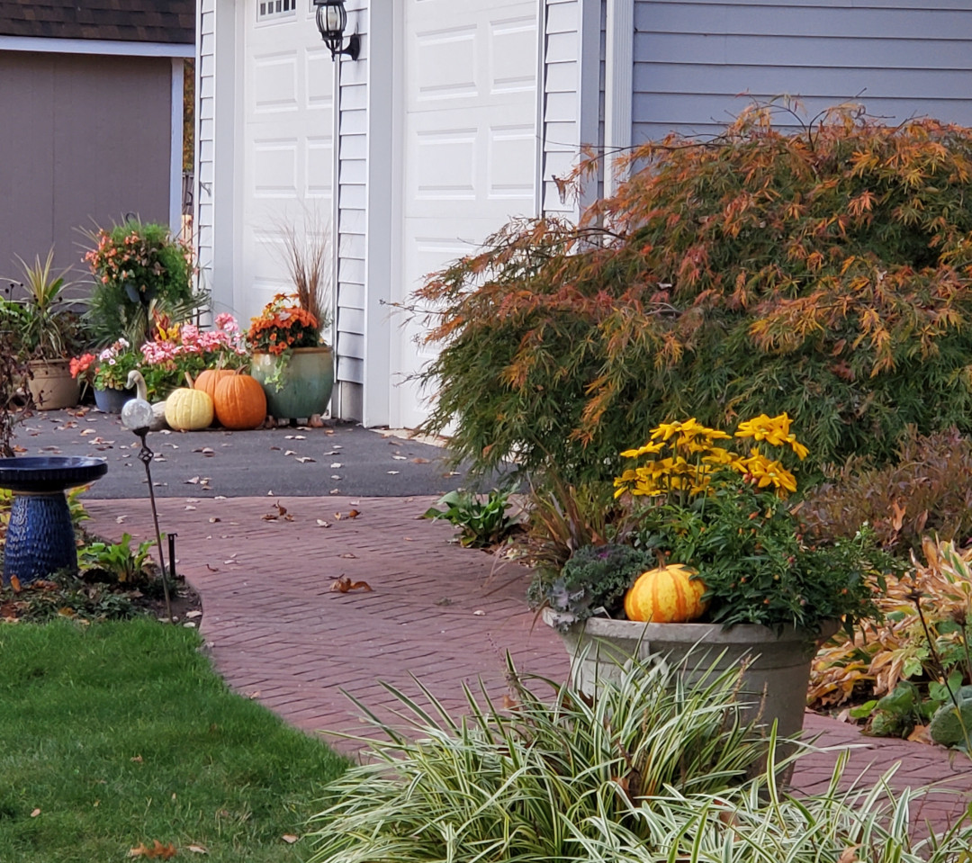 pumpkins and fall container plantings in front of a garage