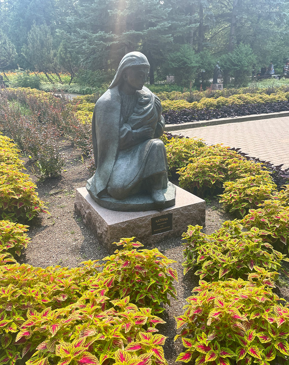 sculpture of mother with baby surrounded by colorful foliage plants