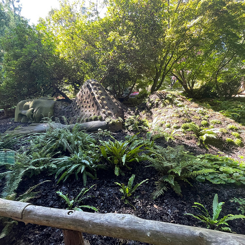 shade garden with plant covered sculpture