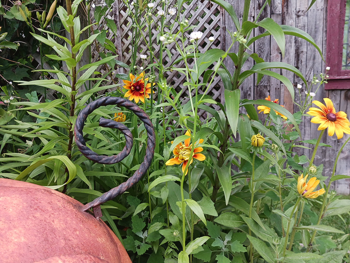 tail of metal pig statue in front of flowers