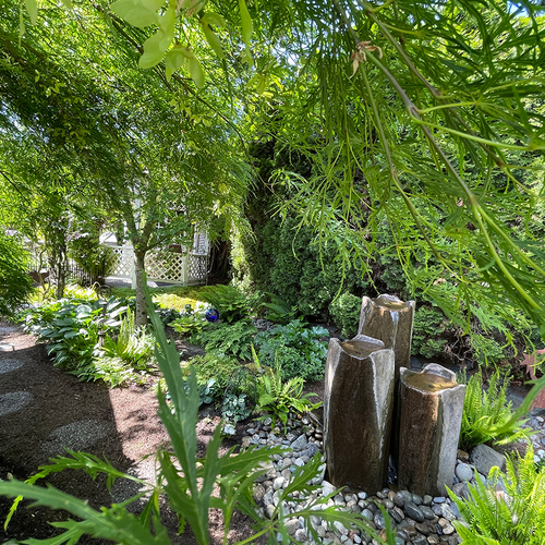 shady garden path with small fountain on one side
