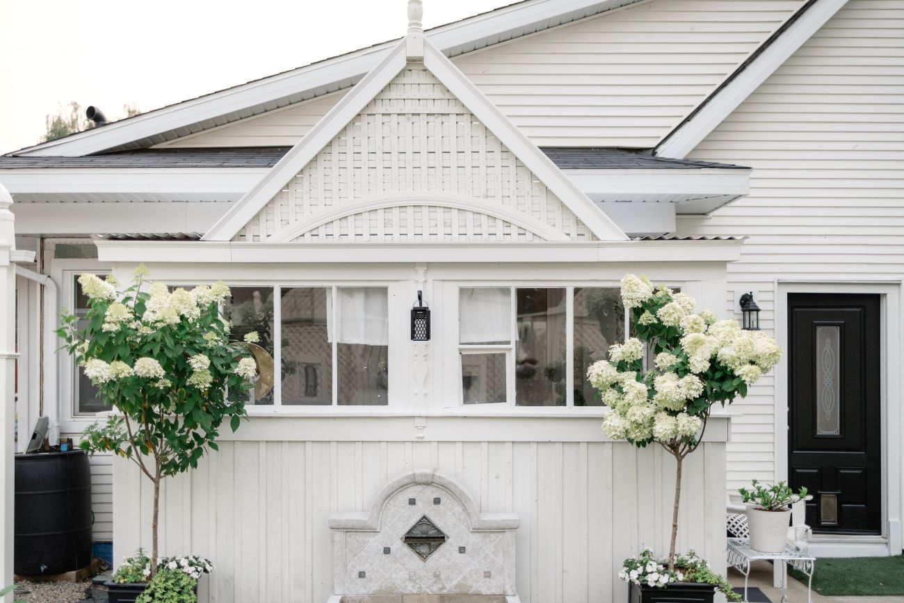 converted white garden room surrounded by blooming hydrangeas