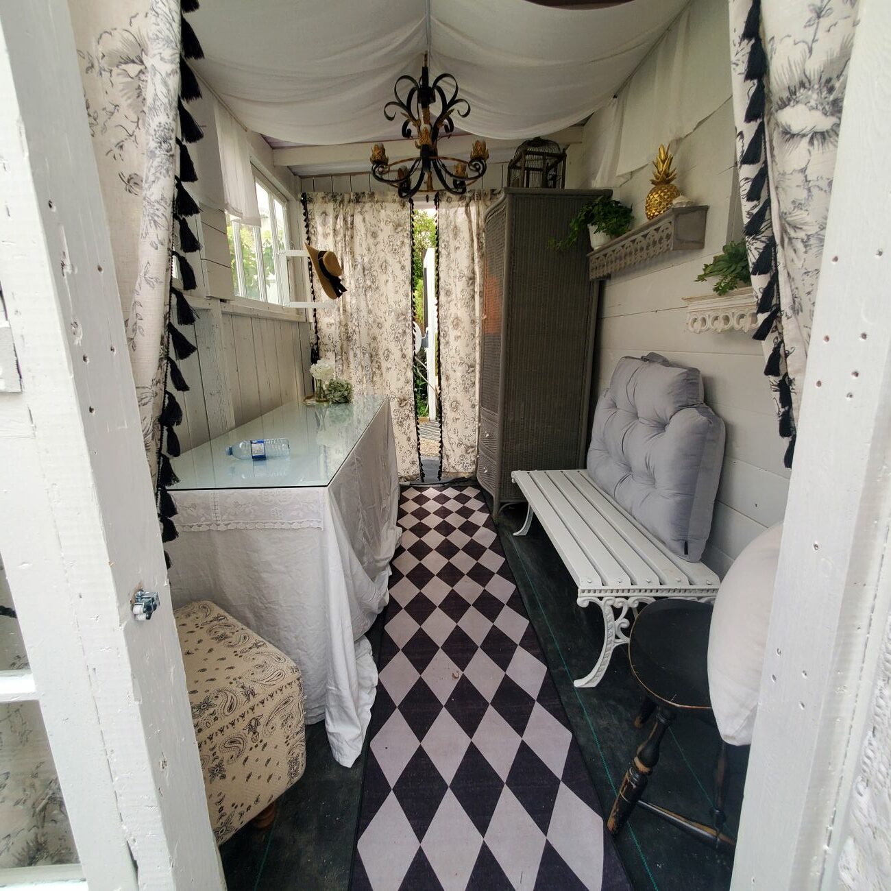 white garden room interior, checkerboard runner, lace curtains, and bench