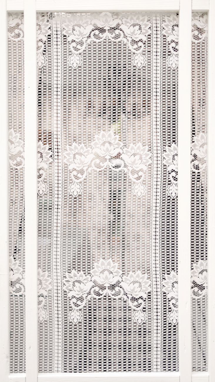 lace-covered upcycled screen door framed by white woodwork