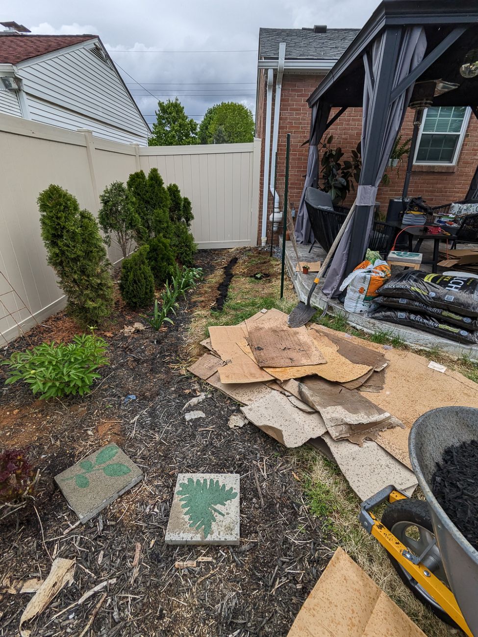 Backyard planting beds being expanded around patio and lawn