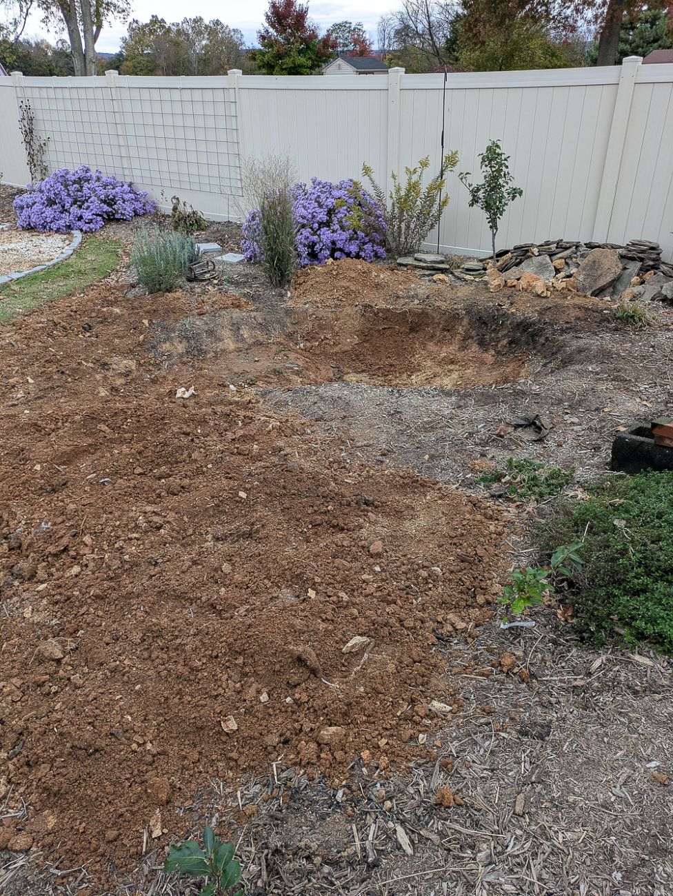 Large pond excavation in backyard garden during fall renovation