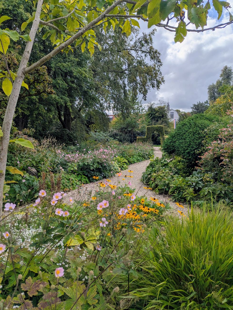 Late-season perennial border beside a winding gravel garden path