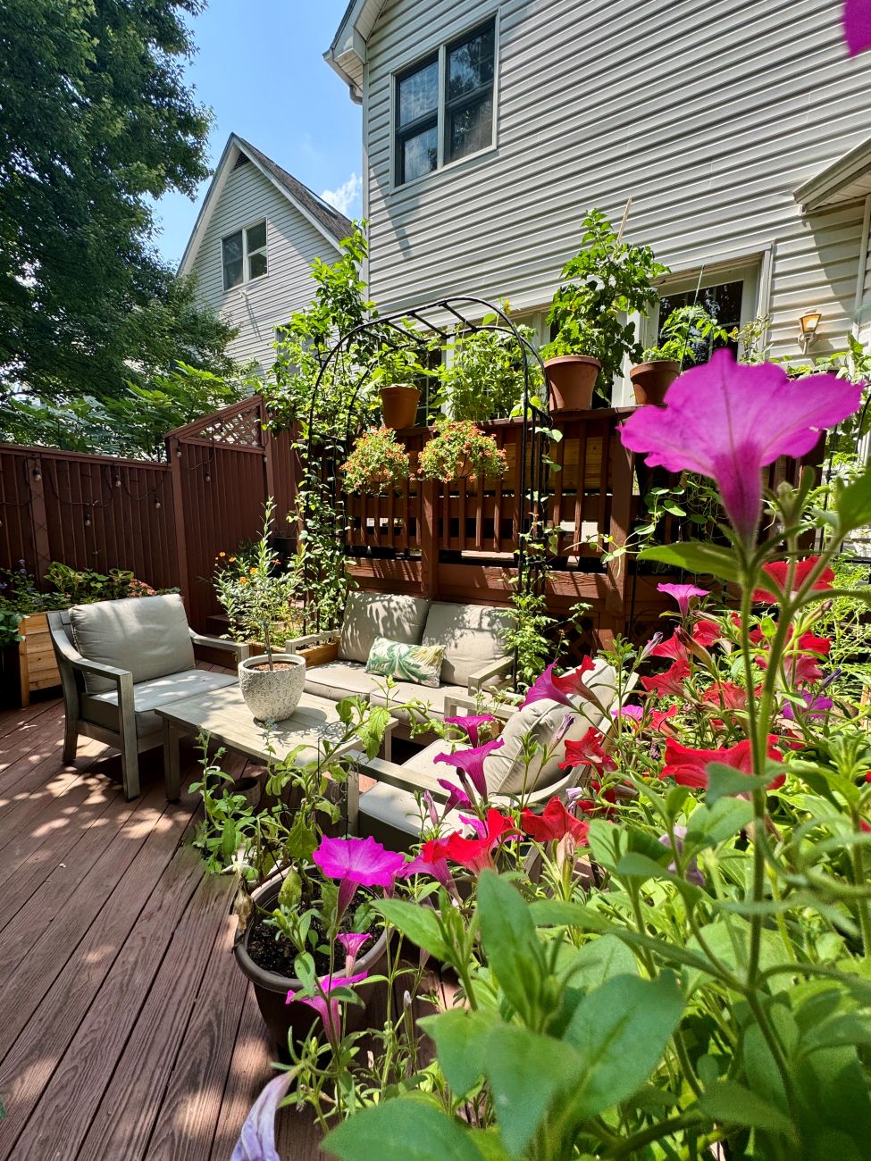Maryland deck garden, outdoor seating area, pink flowers, hanging baskets, lush container plantings, small-space garden retreat