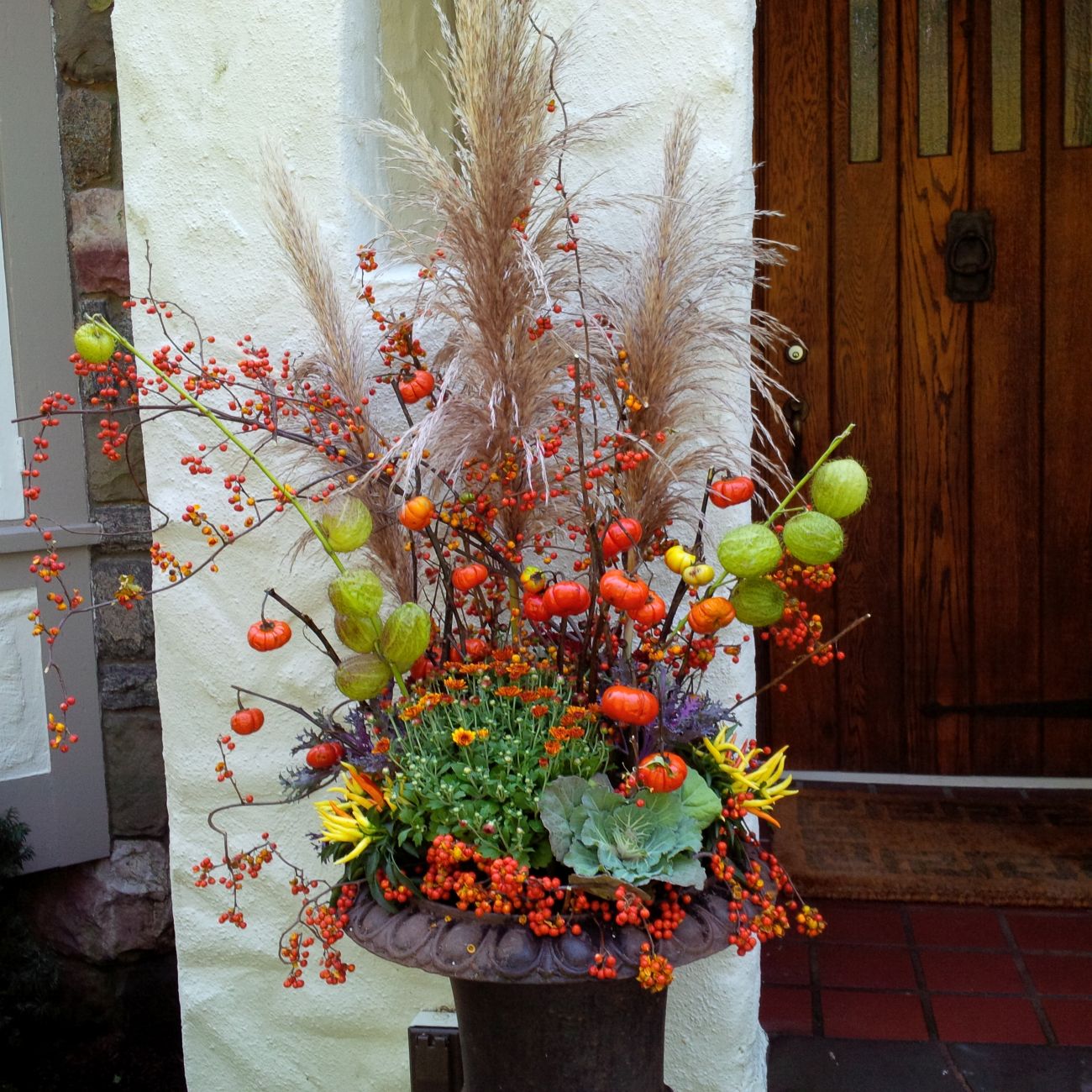 Tall autumn urn, pampas grass plumes, orange bittersweet berries, pumpkins-on-a-stick, balloon plant seed pods, ornamental cabbage