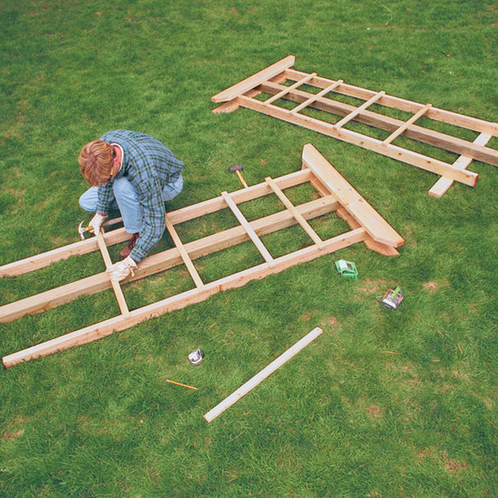 man assembling an arbor on the grass