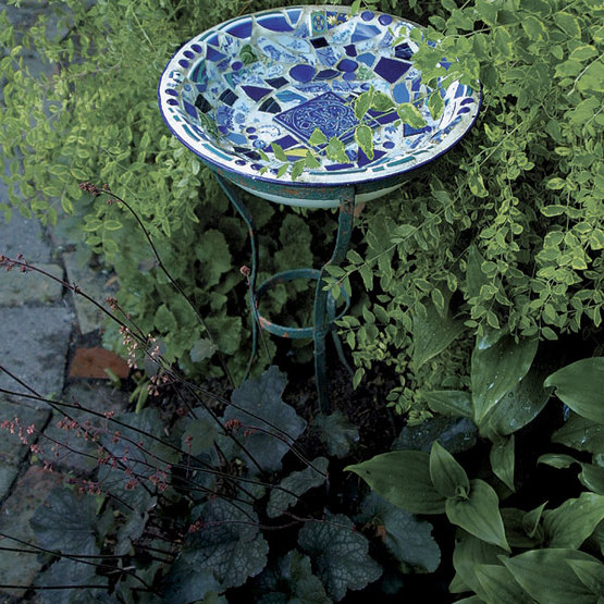 mosaic birdbath nestled in bushes